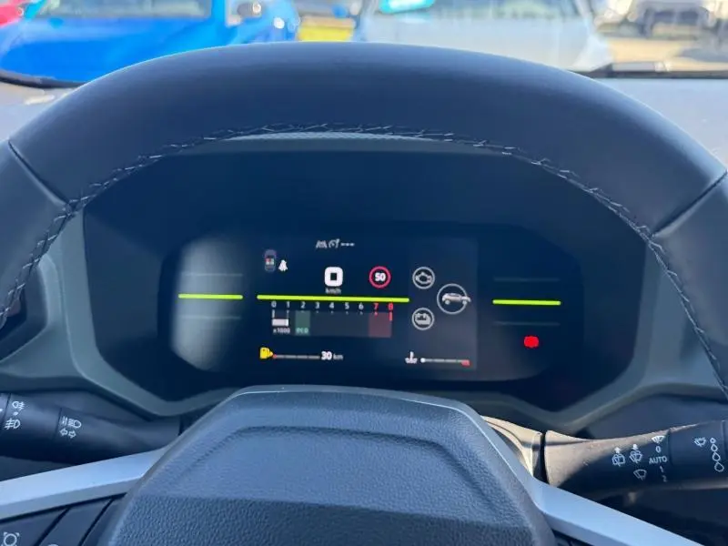 Vue rapprochée du tableau de bord numérique du Dacia Duster 2025, affichage multifonction et volant partiel noir.