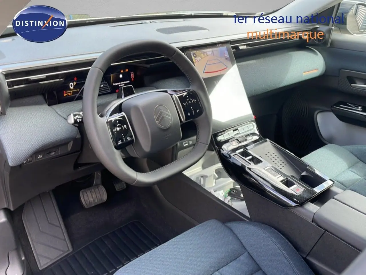 Vue intérieure du tableau de bord et volant du Citroën C5 Aircross Hybrid, avec sellerie tissu bleu et console centrale brillante noire.
