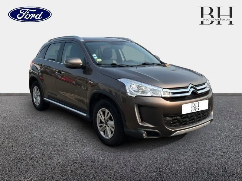 Citroën C4 Aircross brun Mangaro vue 3/4 avant droit avec calandre chromée et barres de toit visibles.