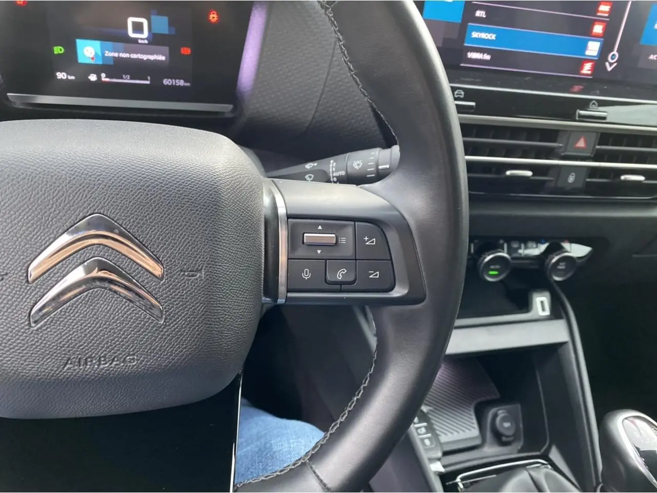 Gros plan sur le volant noir de la Citroën C4 2021 avec commandes intégrées et tableau de bord numérique en arrière-plan.