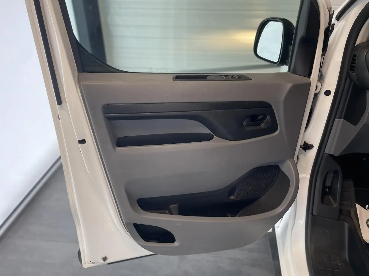 Vue en gros plan de la porte avant gauche blanche de l'Opel Vivaro avec commandes de vitres et rangement intégré.