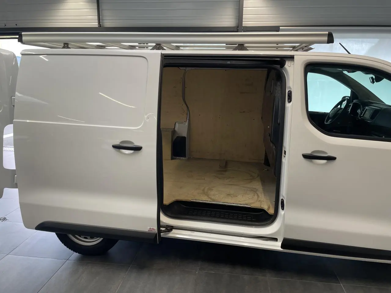 Vue de profil droit d'un Opel Vivaro blanc avec porte latérale coulissante ouverte montrant l'espace de chargement vide.