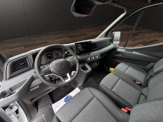 Vue intérieure côté conducteur du Renault Master blanc 2025, avec tableau de bord moderne et sièges tissu gris chiné.