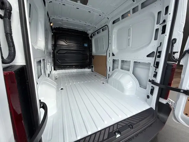 Vue intérieure arrière du Renault Master blanc 2025, montrant l'espace de chargement vide avec cloison tôlée noire.