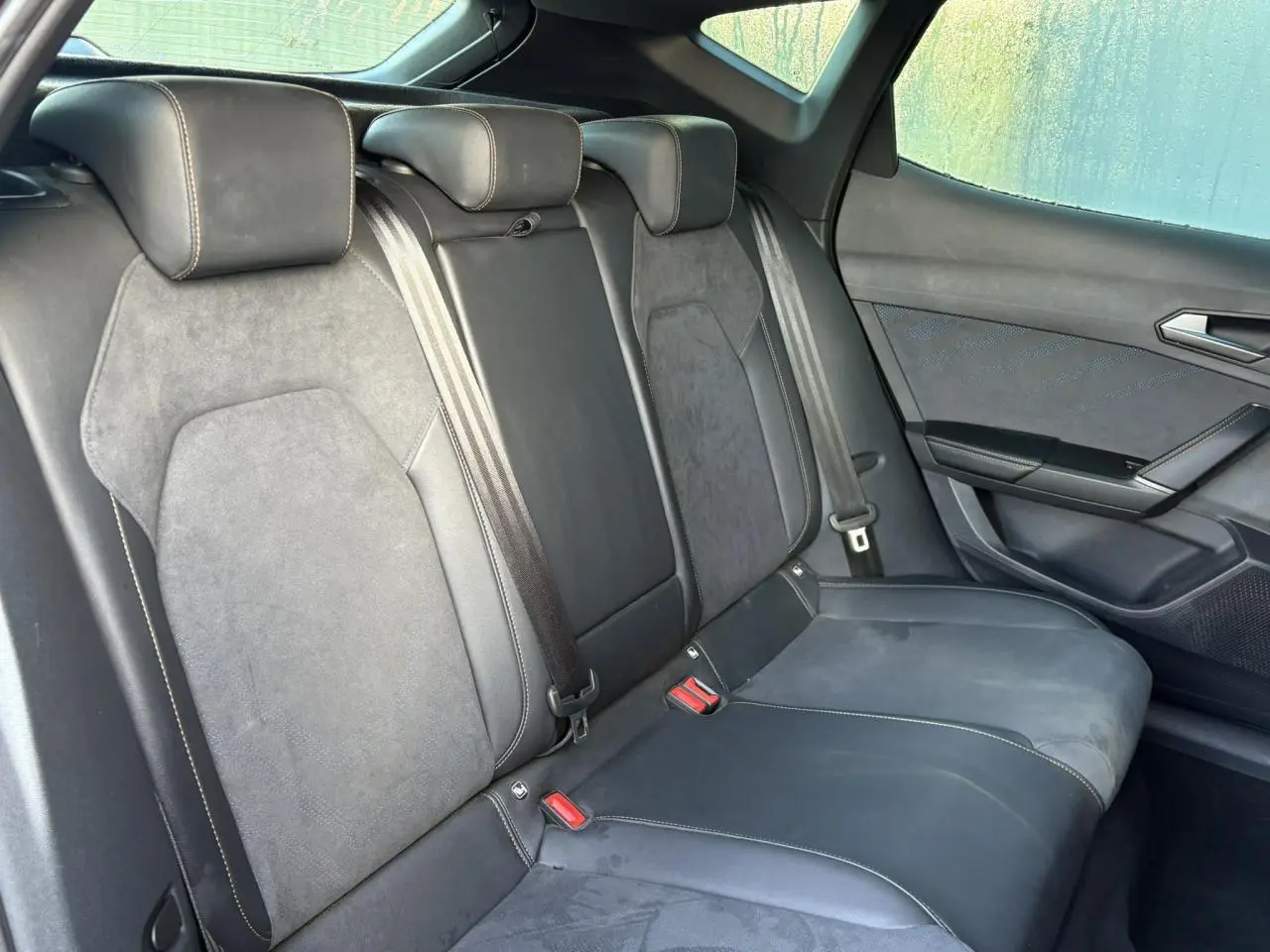 Vue côté droit des sièges arrière en suédine noir asphalte du CUPRA Formentor gris magnétique, avec ceintures et appuie-têtes visibles.