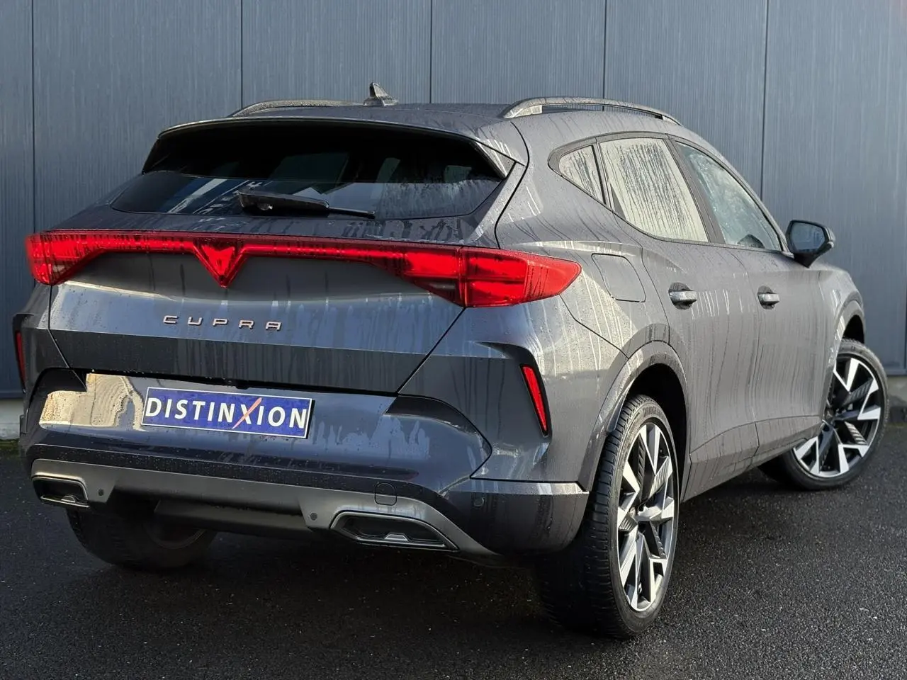 Vue 3/4 arrière droite d'une CUPRA Formentor blanche avec feux arrière en bandeau lumineux et jantes alliage noires et argent.