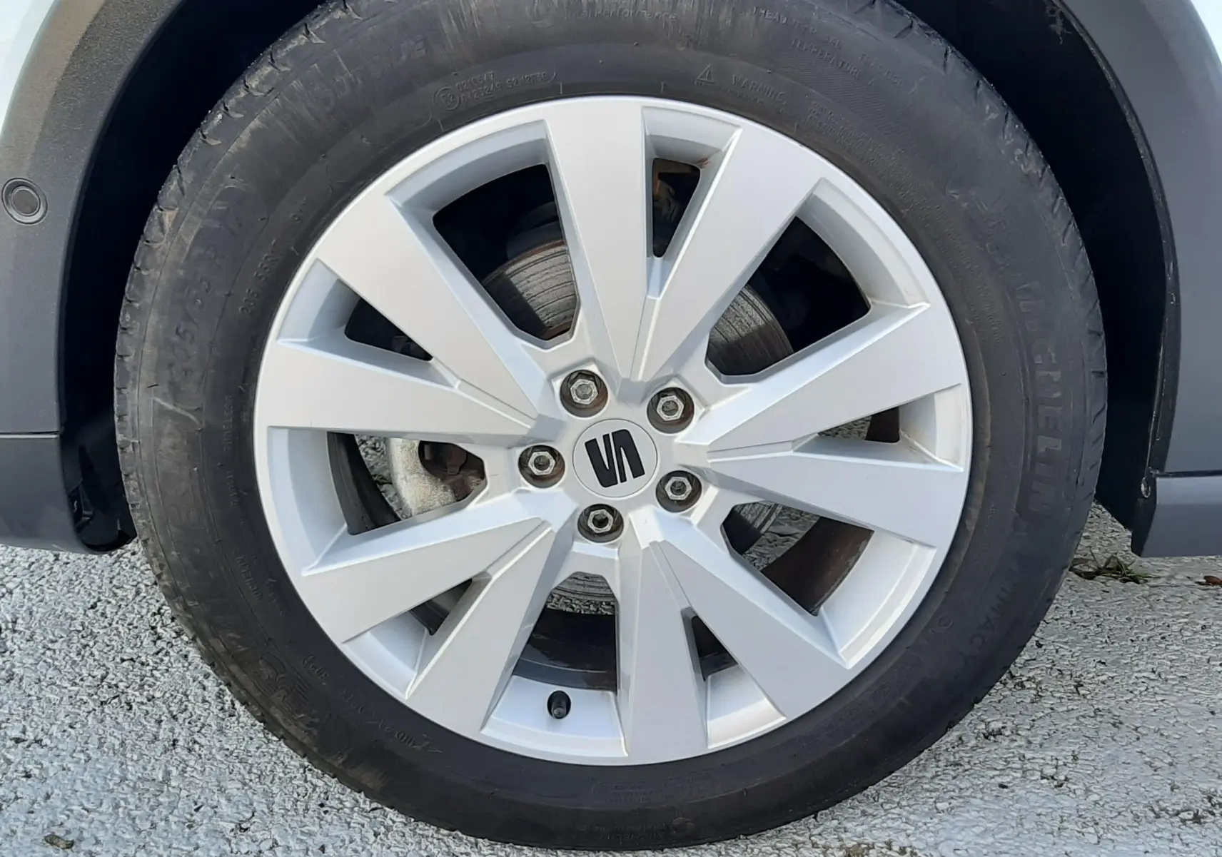 Gros plan sur la jante alliage argentée avec logo SEAT d’un SEAT Arona 2025 blanc Nevada toit gris.