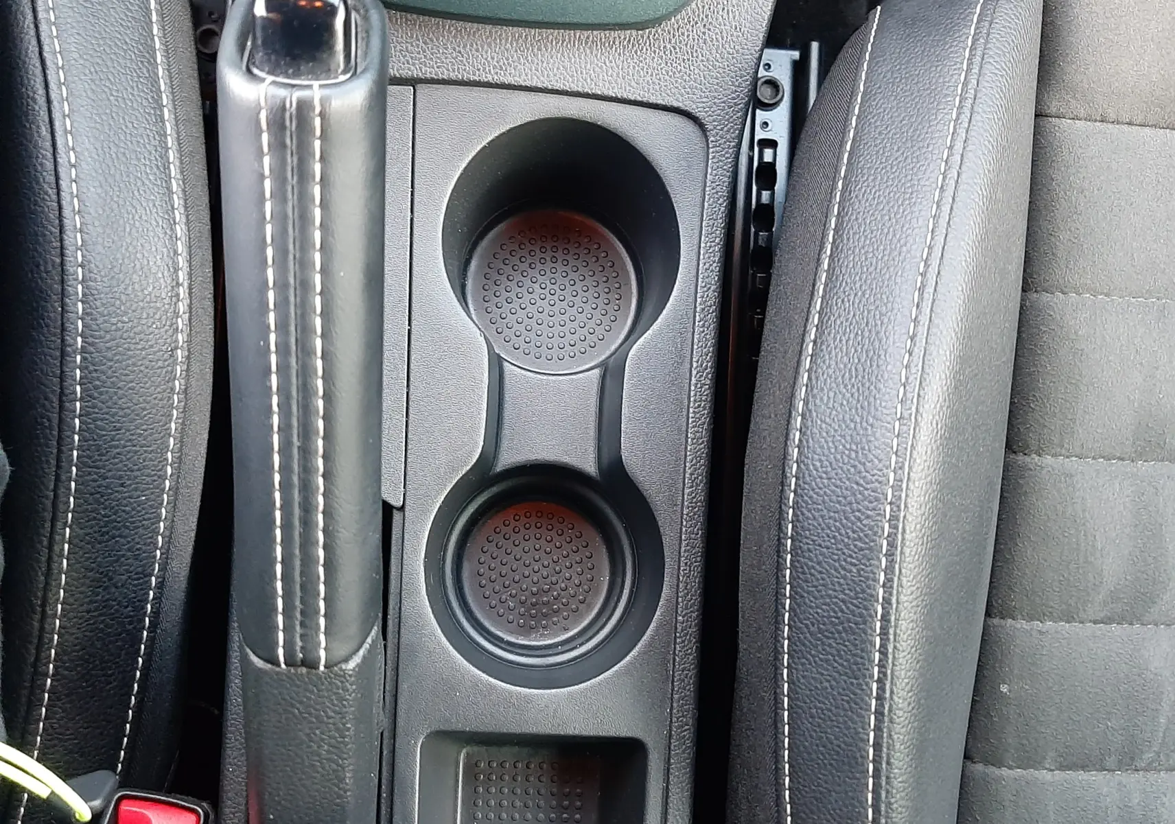 Vue plongeante sur la console centrale noire du SEAT Arona 2025, montrant frein à main, porte-gobelets et siège conducteur.