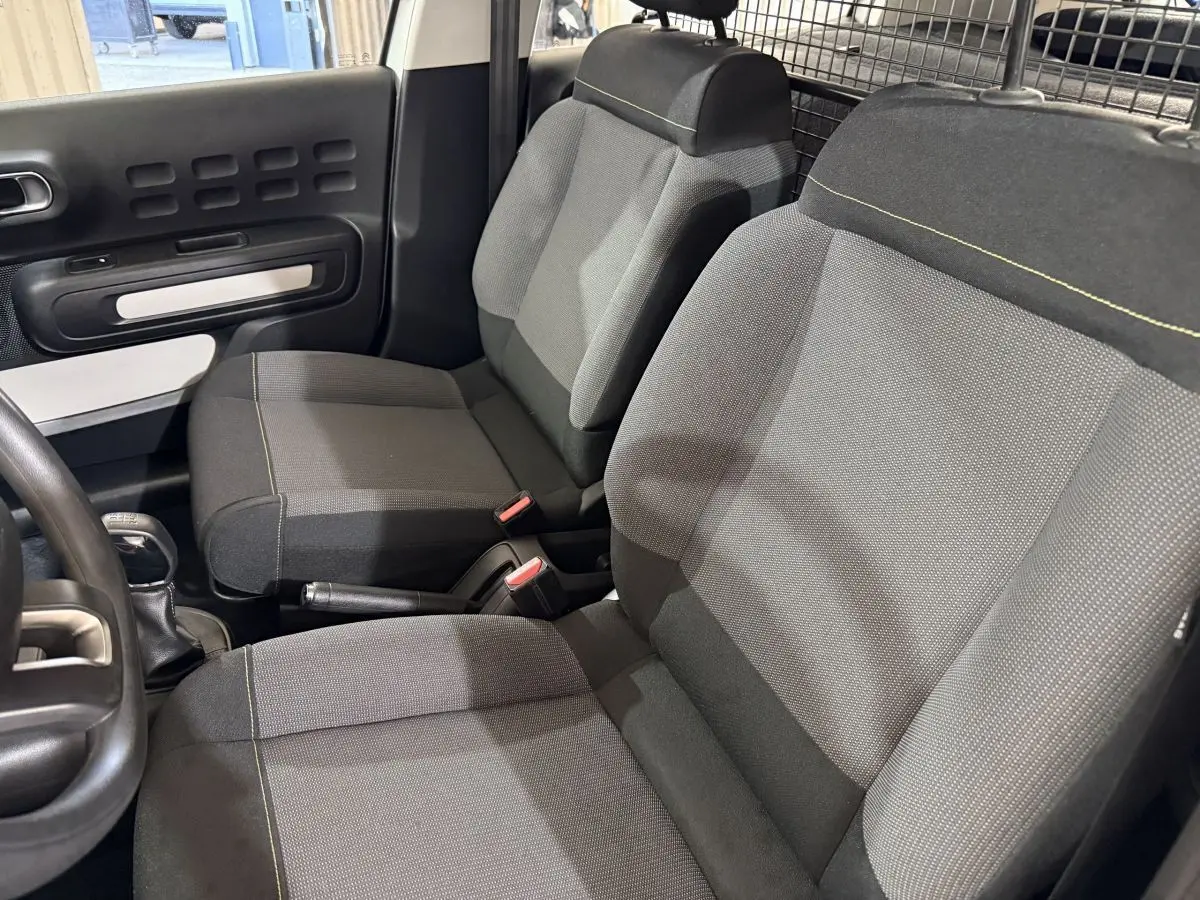 Vue intérieure côté conducteur de la Citroën C3 2021, sièges tissu gris avec surpiqûres jaunes et séparation grillagée.