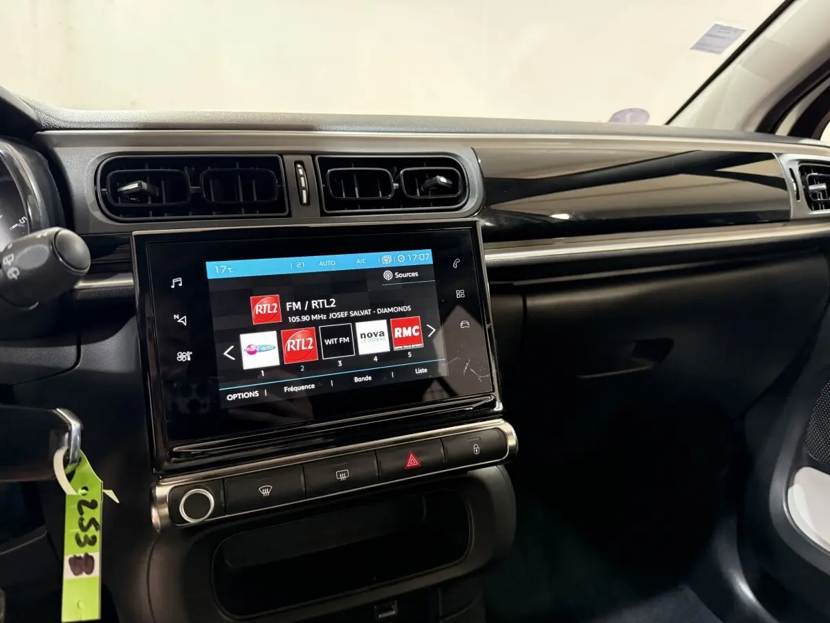 Vue intérieure du tableau de bord de la Citroën C3 blanche, avec écran tactile central affichant des stations radio.
