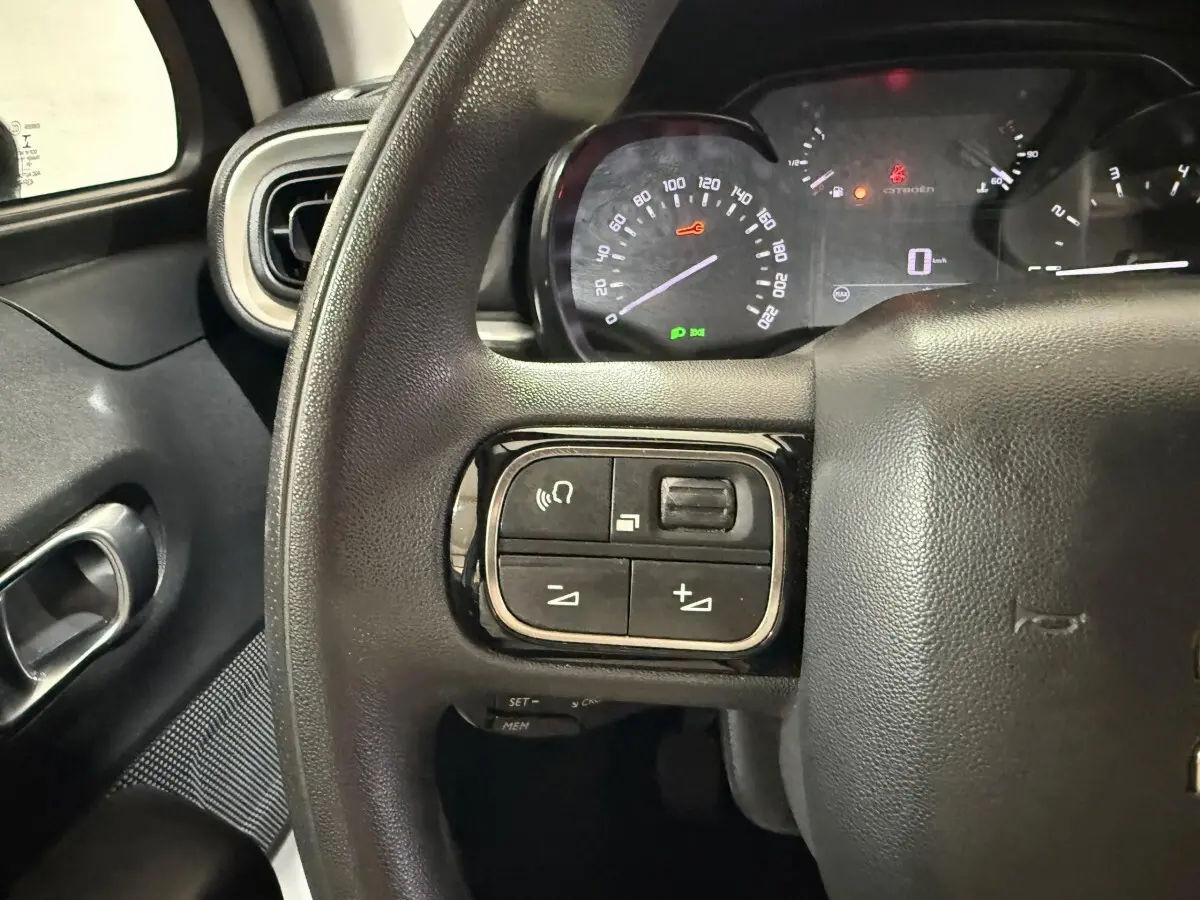 Gros plan sur le volant noir de la Citroën C3 2021 avec commandes intégrées et tableau de bord lumineux en arrière-plan.