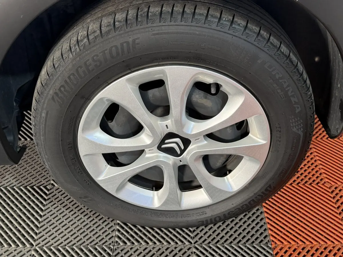 Gros plan sur la roue avant gauche d'une Citroën C3 blanche avec jante argentée et logo Citroën central.