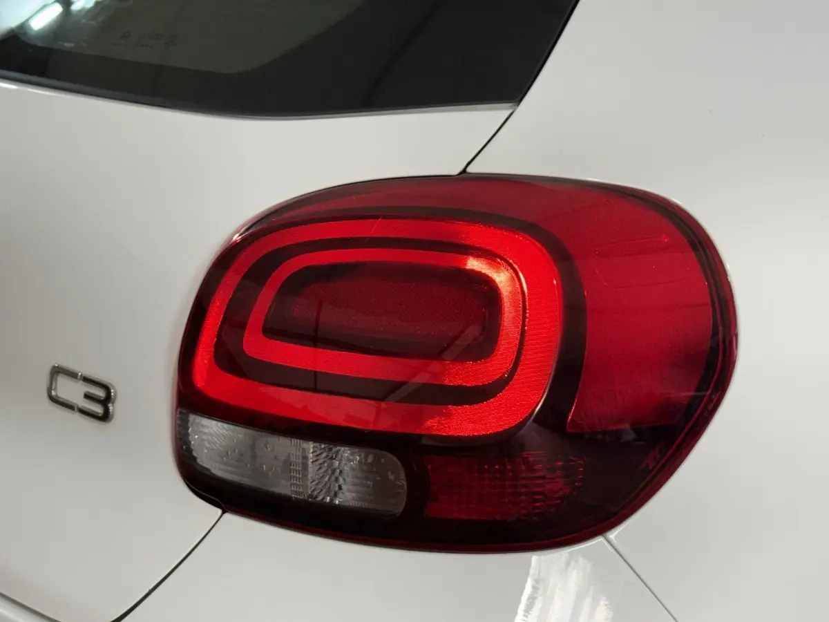 Gros plan sur le feu arrière droit rouge d’une Citroën C3 blanche, avec le logo C3 visible sur la carrosserie.