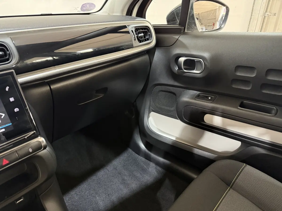 Intérieur côté passager de la Citroën C3 blanc, tableau de bord noir brillant et garniture de porte bicolore.