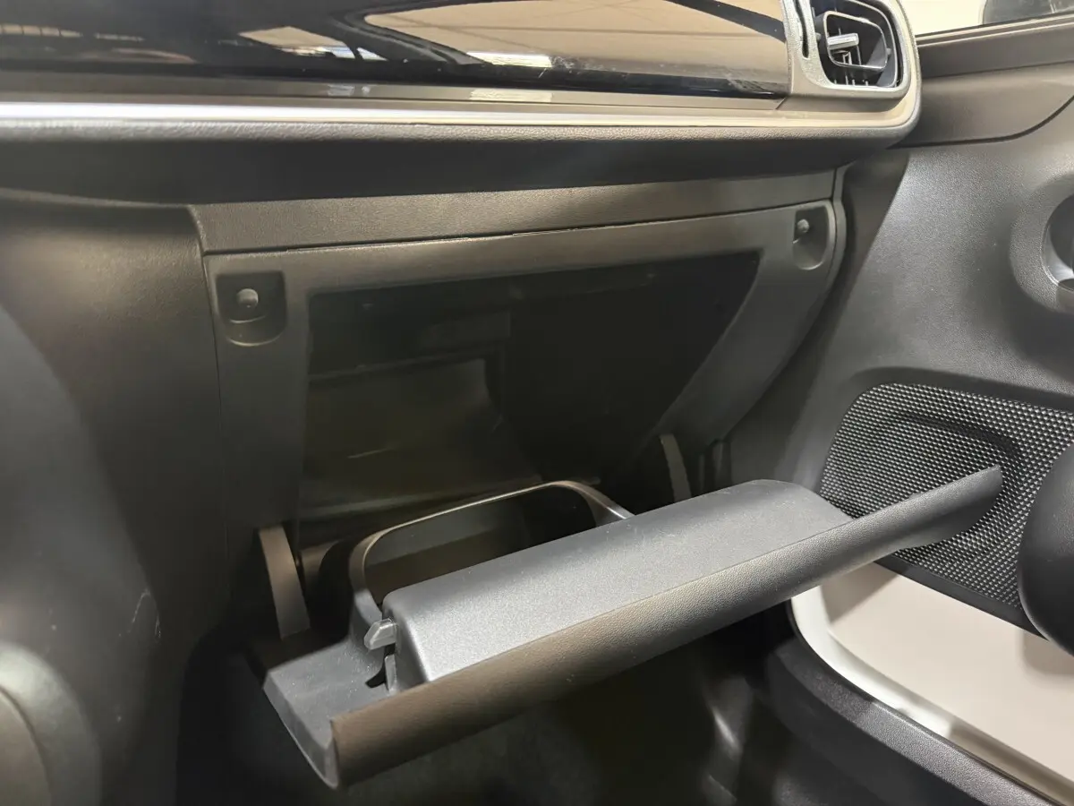 Vue intérieure côté passager de la boîte à gants ouverte dans une Citroën C3 blanche, tableau de bord noir.