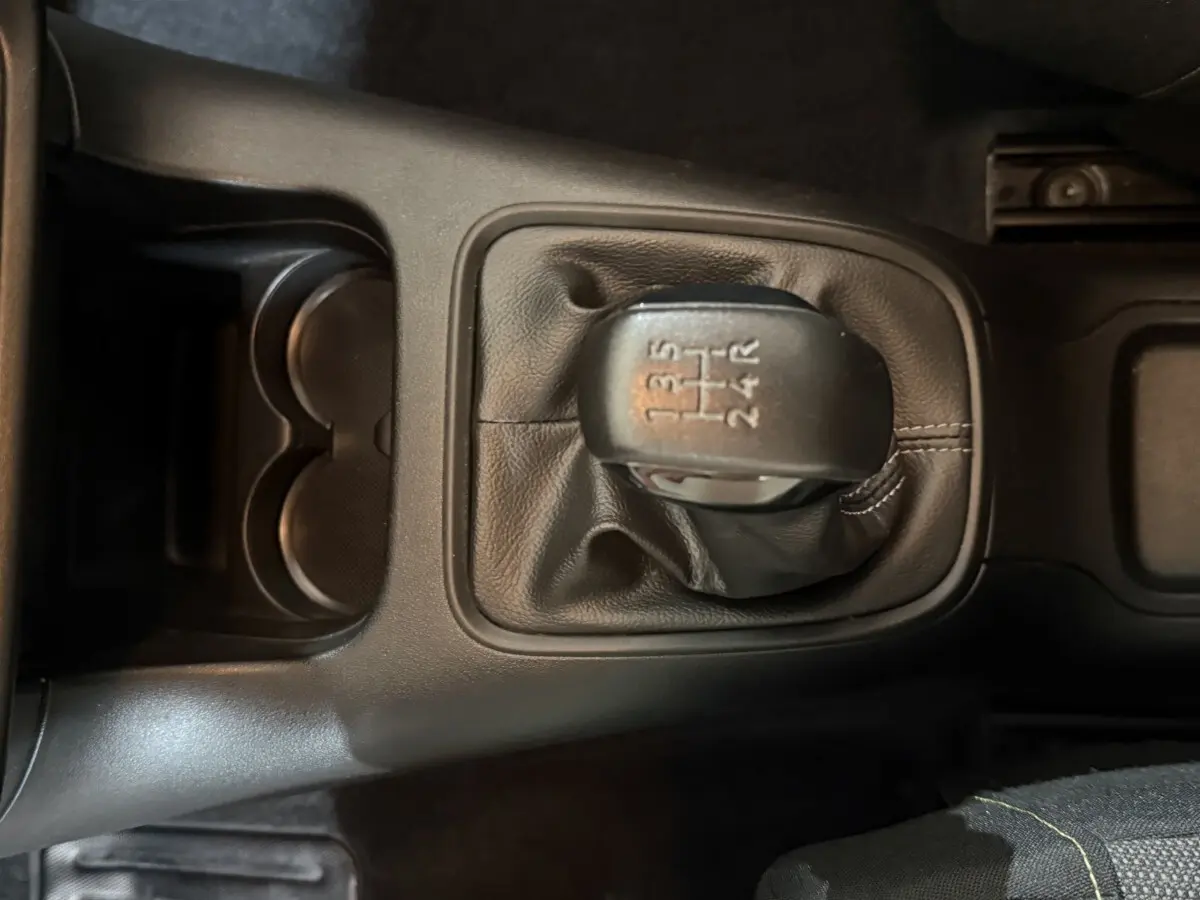 Gros plan sur le levier de vitesses manuel noir de la Citroën C3 blanche, avec console centrale et porte-gobelets visibles.