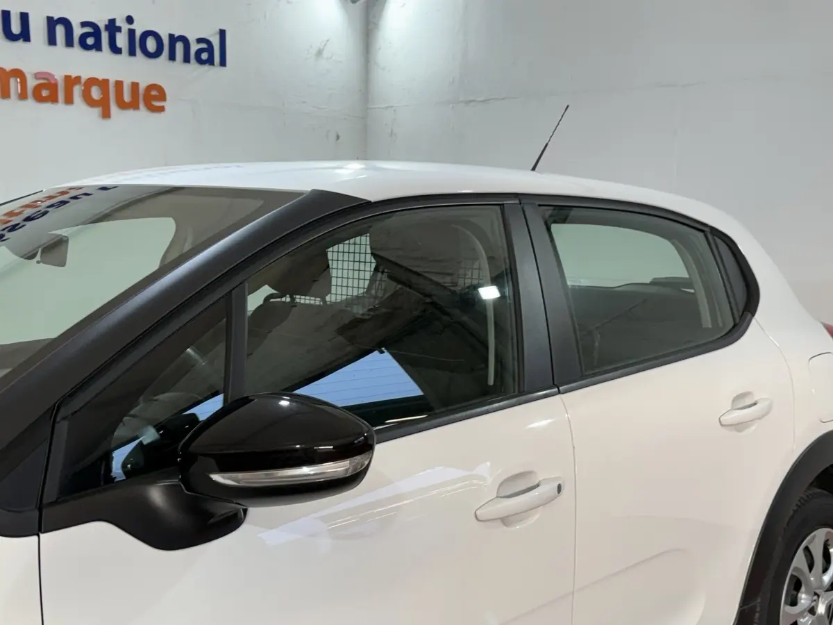 Vue latérale côté gauche d'une Citroën C3 blanche avec rétroviseur noir et poignées de porte assorties.