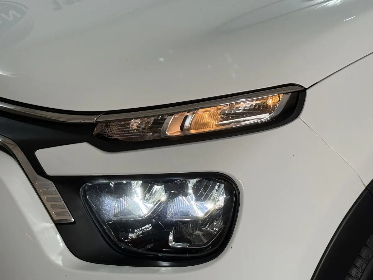 Gros plan sur le phare avant droit blanc de la Citroën C3 2021 avec feux LED allumés et clignotant orange.