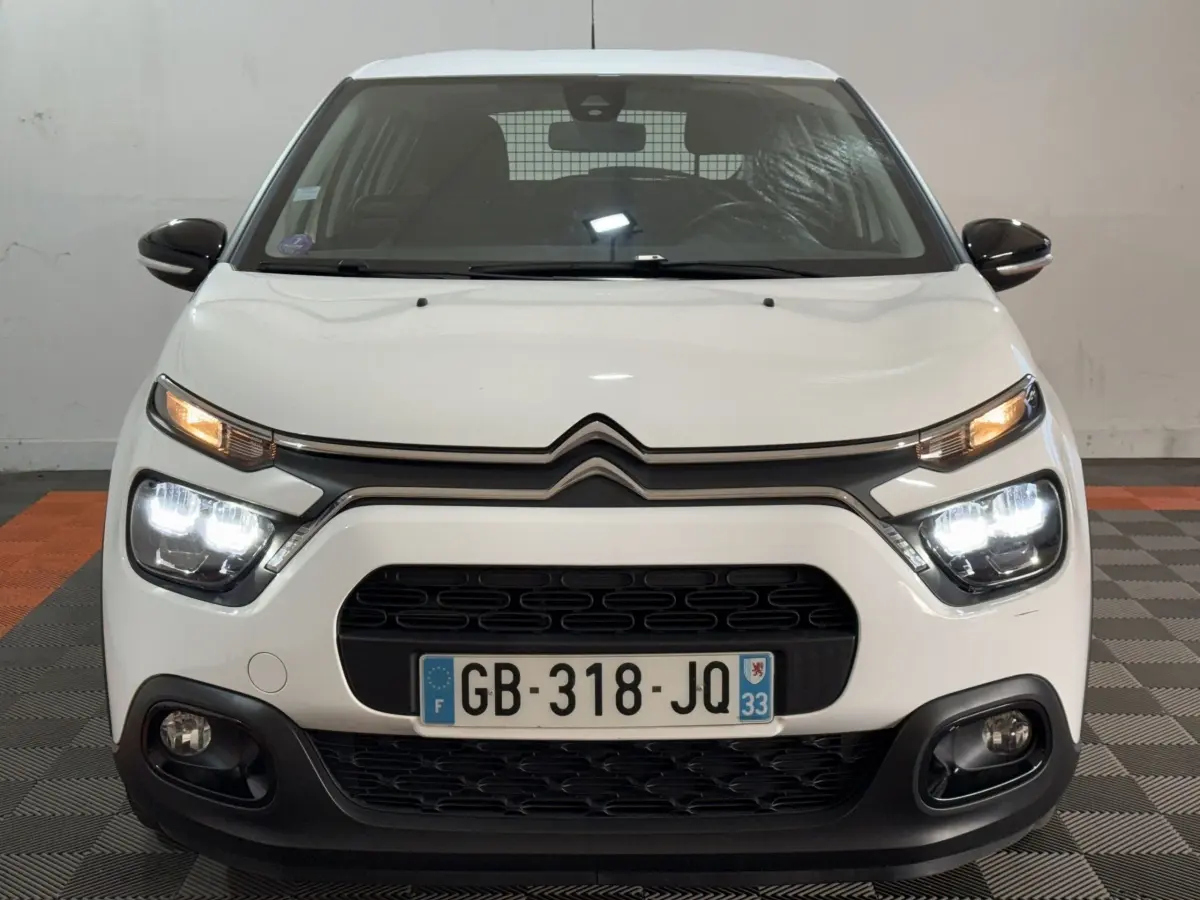 Vue frontale d'une Citroën C3 blanche avec phares LED allumés et calandre noire distinctive.