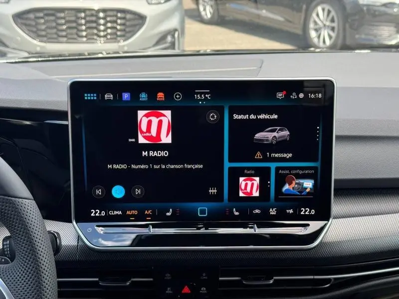 Vue intérieure centrée sur l'écran tactile multifonction de la Volkswagen Golf 1.5 eTSI R-Line gris lunaire, affichant la radio et le statut véhicule.