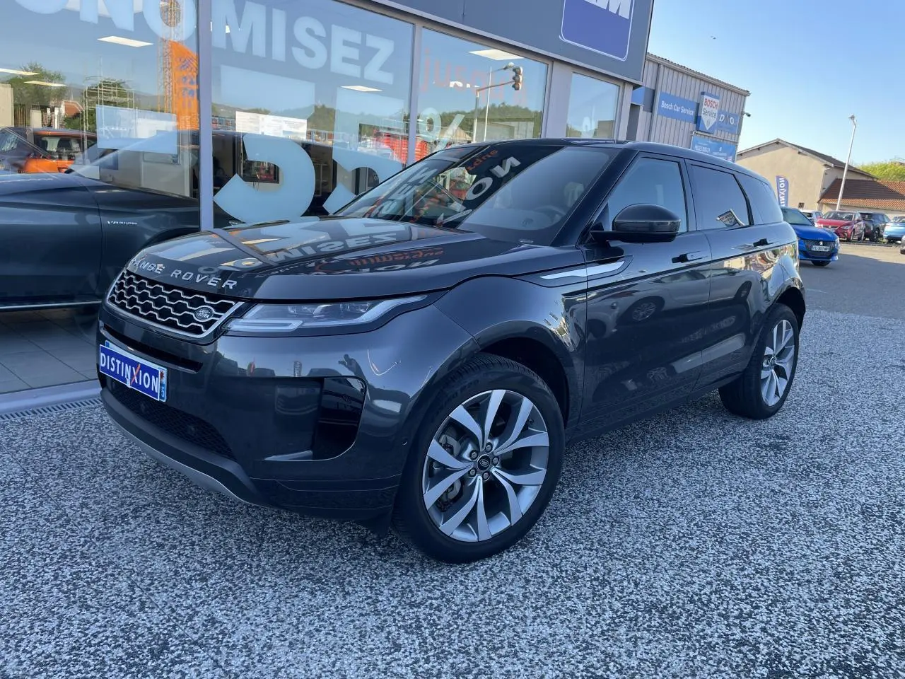 Range Rover Evoque gris métallisé vu en 3/4 avant droit, avec calandre Dark Atlas et jantes 20 pouces cinq branches.