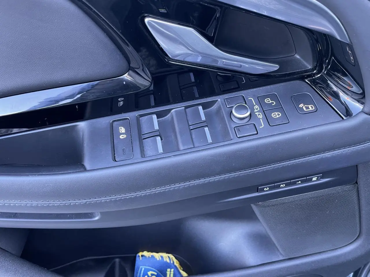 Gros plan sur la porte côté gauche du Range Rover Evoque gris, montrant les commandes des vitres et rétroviseurs.