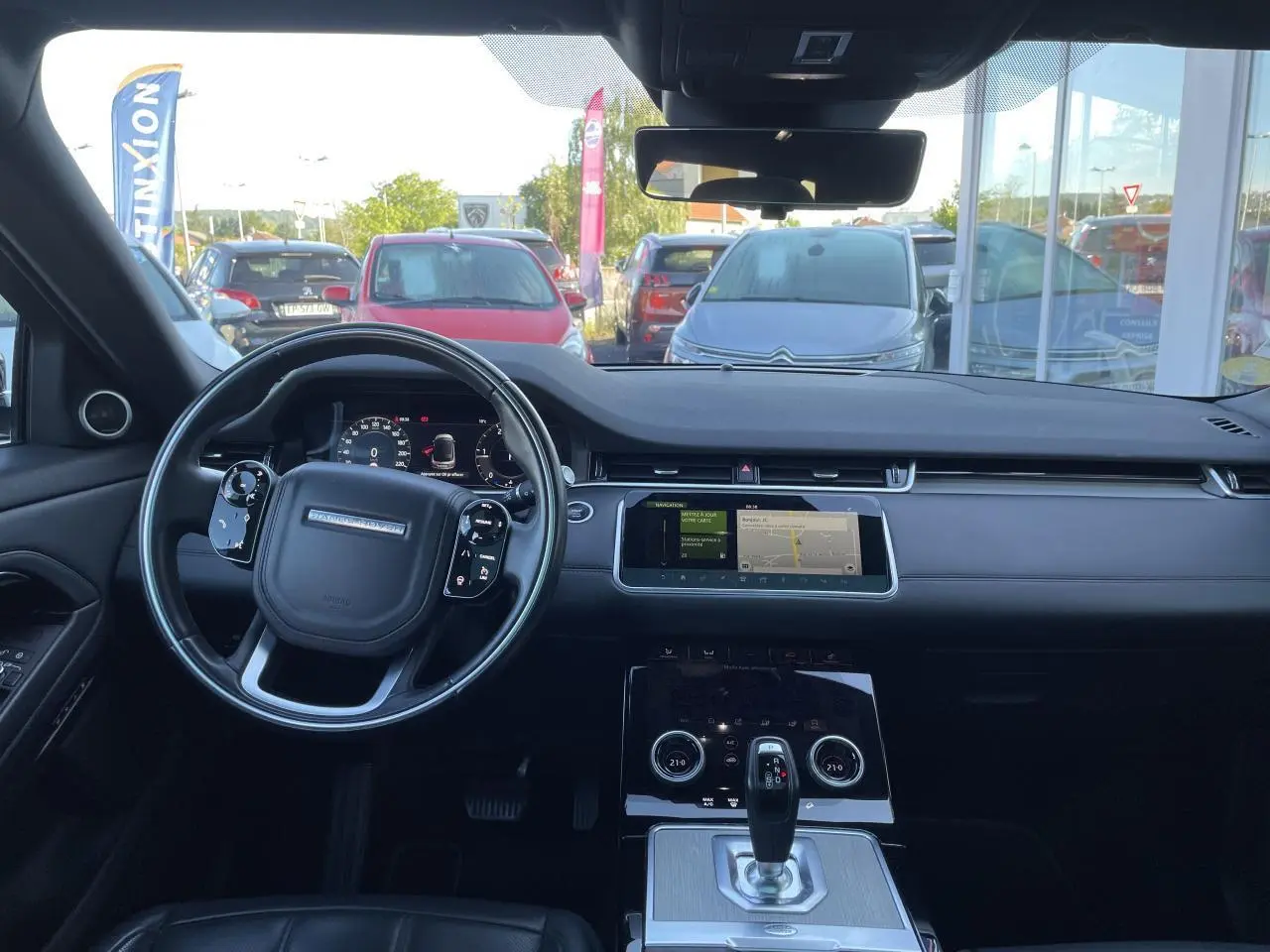 Tableau de bord et volant noir du Range Rover Evoque 2019 vus de face avec écran tactile central allumé.