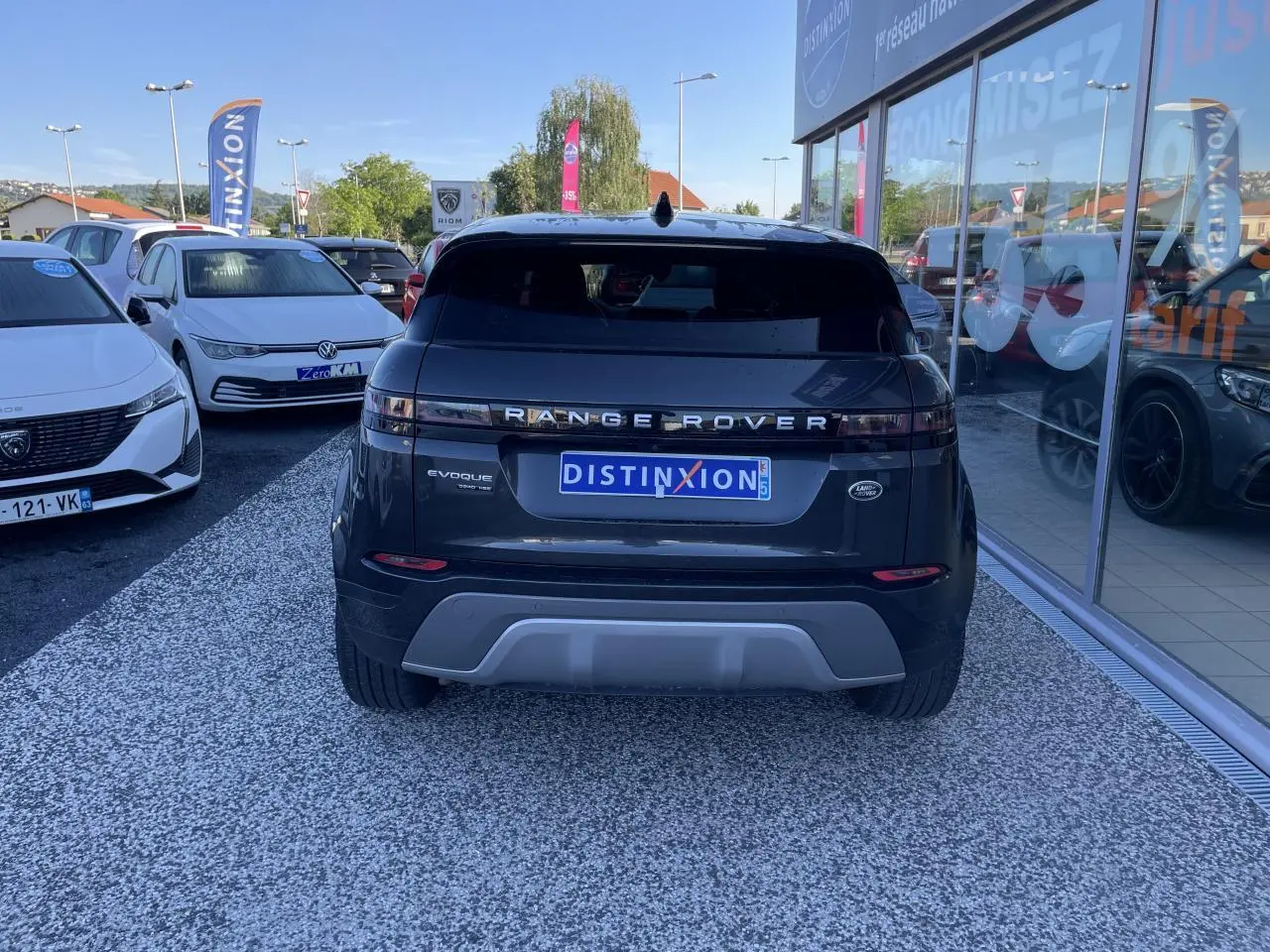 Vue arrière d'un Range Rover Evoque gris métallisé avec logo et plaque Distinxion visible en concession.