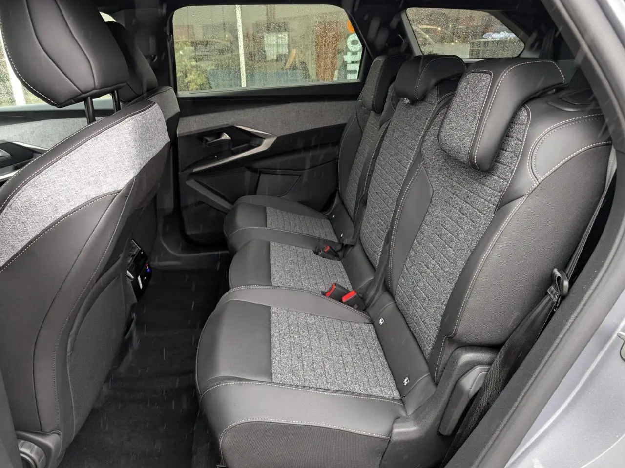 Vue latérale intérieure sur la banquette arrière tissu gris et cuir noir du Peugeot 5008 Gris Artense 2025.