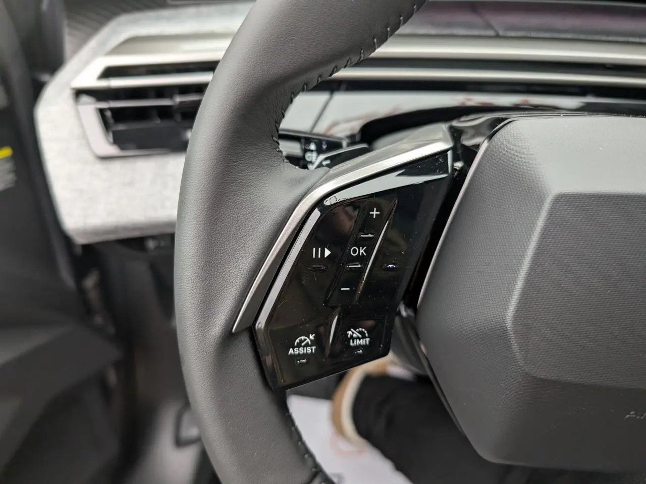 Gros plan sur la partie gauche du volant cuir noir du Peugeot 5008 gris Artense avec commandes intégrées.