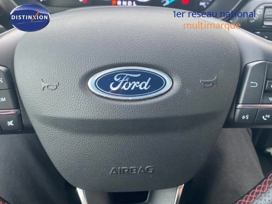 Gros plan sur le volant noir de la Ford Focus 2024, avec logo Ford central et commandes intégrées.