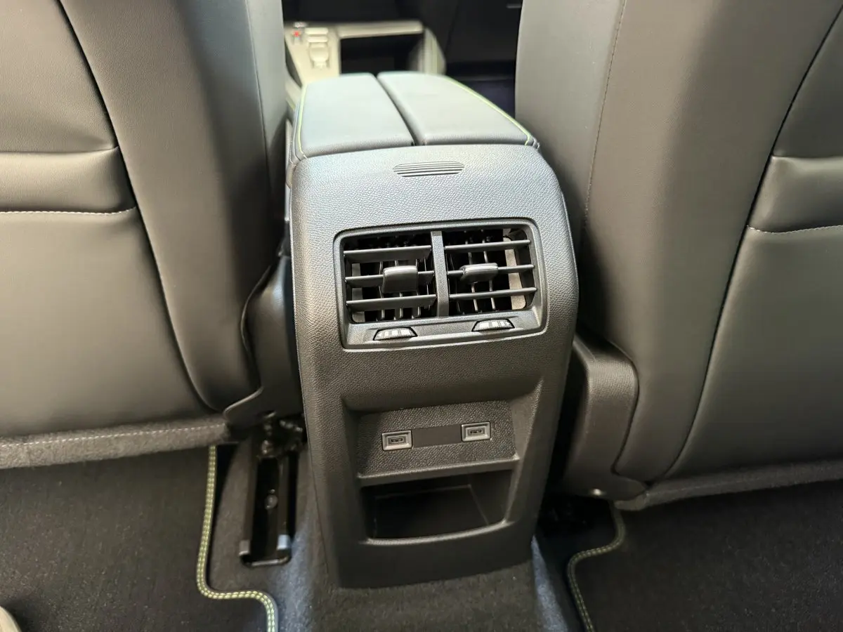 Vue rapprochée de la console centrale arrière avec aérateurs et ports USB dans l’habitacle gris foncé d’une Peugeot 308 Hybrid 2024.