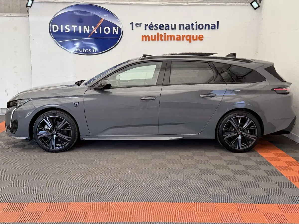 Profil latéral droit d'une Peugeot 308 Hybrid 136 e-DCS6 GT gris foncé avec jantes noires et toit ouvrant panoramique.