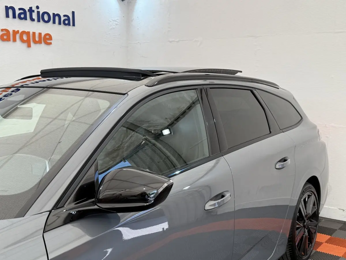 Vue latérale droite d’un Peugeot 308 Hybrid 136 e-DCS6 GT gris foncé avec rétroviseur noir brillant et toit ouvrant.