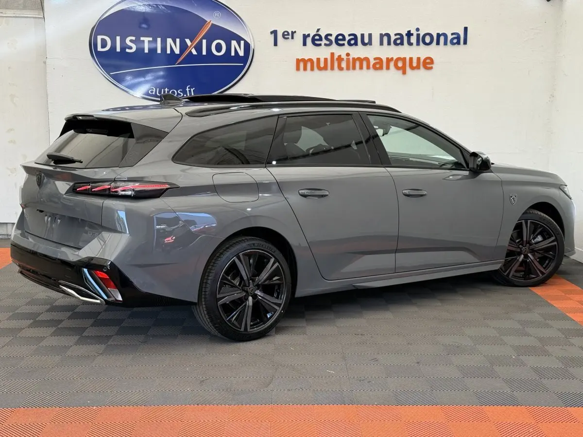 Peugeot 308 Hybrid 136 e-DCS6 GT gris foncé vue 3/4 arrière droit, jantes noires et toit ouvrant panoramique.