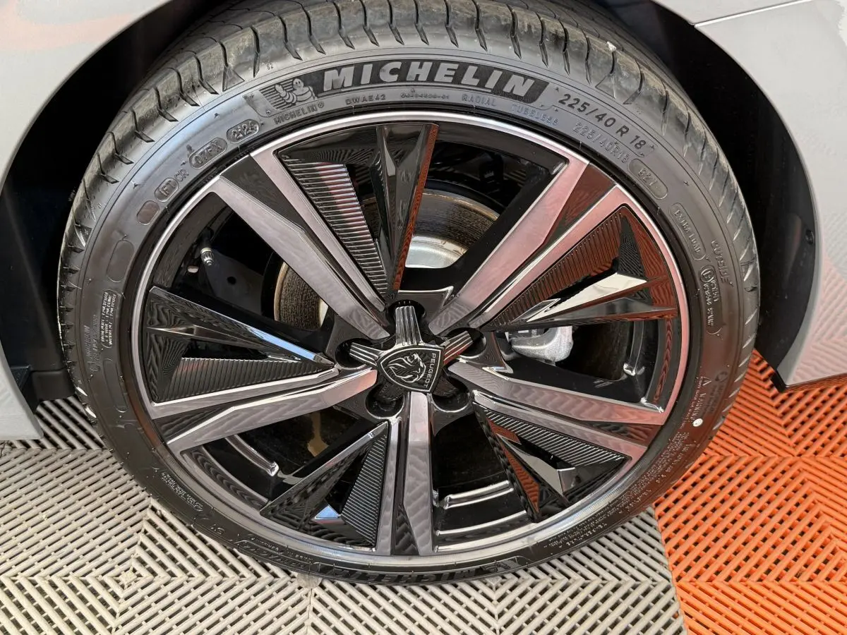Gros plan sur la jante noire et argentée de la Peugeot 308 Hybrid 136 e-DCS6 GT gris foncé, avec pneu Michelin.