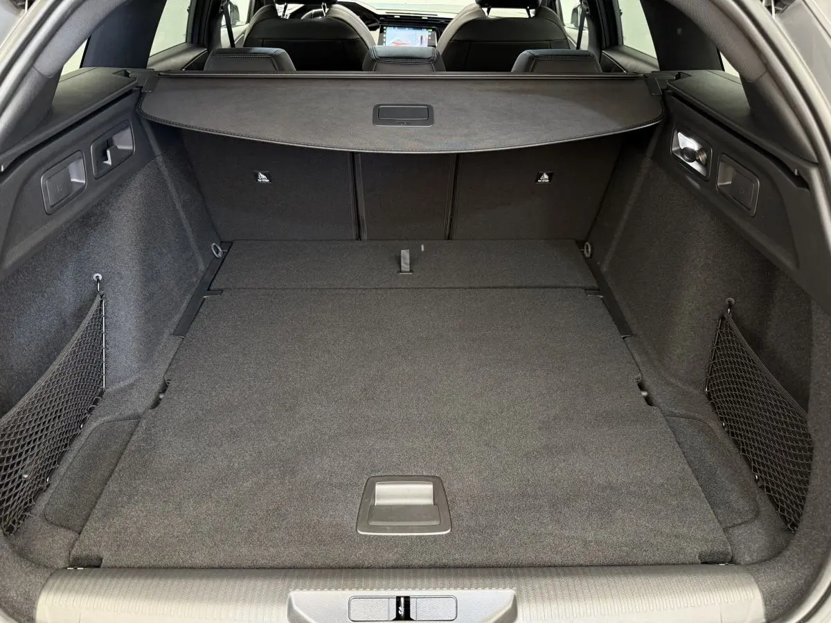 Coffre spacieux et plancher plat du Peugeot 308 Hybrid 136 e-DCS6 GT vu de l'arrière, intérieur gris foncé.