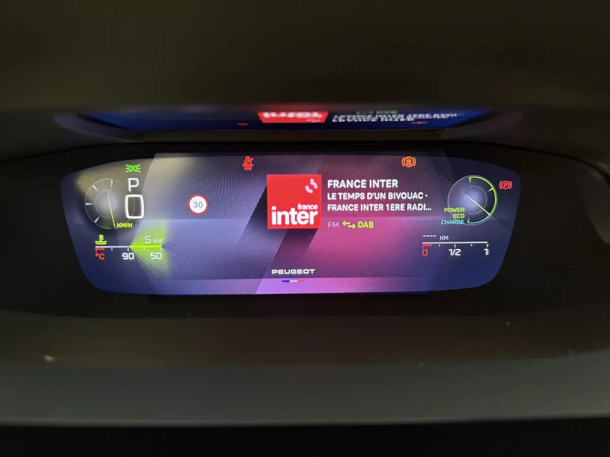 Affichage numérique 10 pouces du combiné instruments Peugeot 308 Hybrid 2024, montrant vitesse, radio et indicateurs énergie.