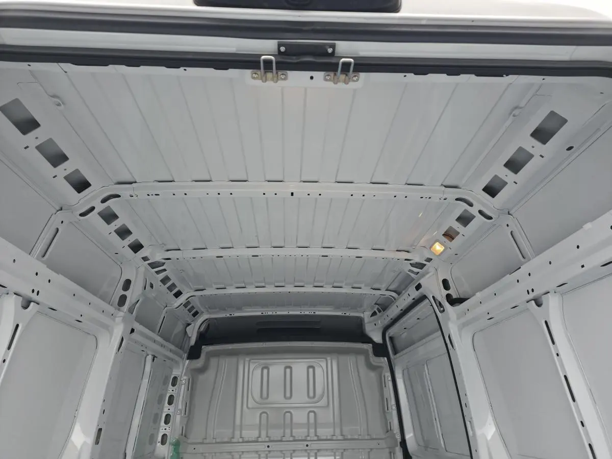 Vue intérieure du coffre blanc du Peugeot Boxer Fourgon 2025, montrant la structure tôlée et l'éclairage intérieur.