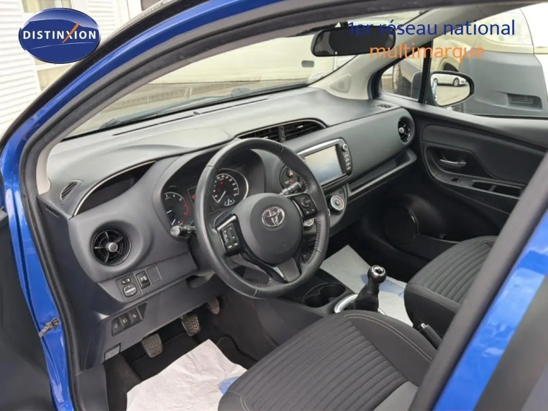 Vue intérieure côté conducteur de la Toyota Yaris MC2 69 VVT-i Design 2018 bleu foncé, volant multifonctions et boîte manuelle visibles.
