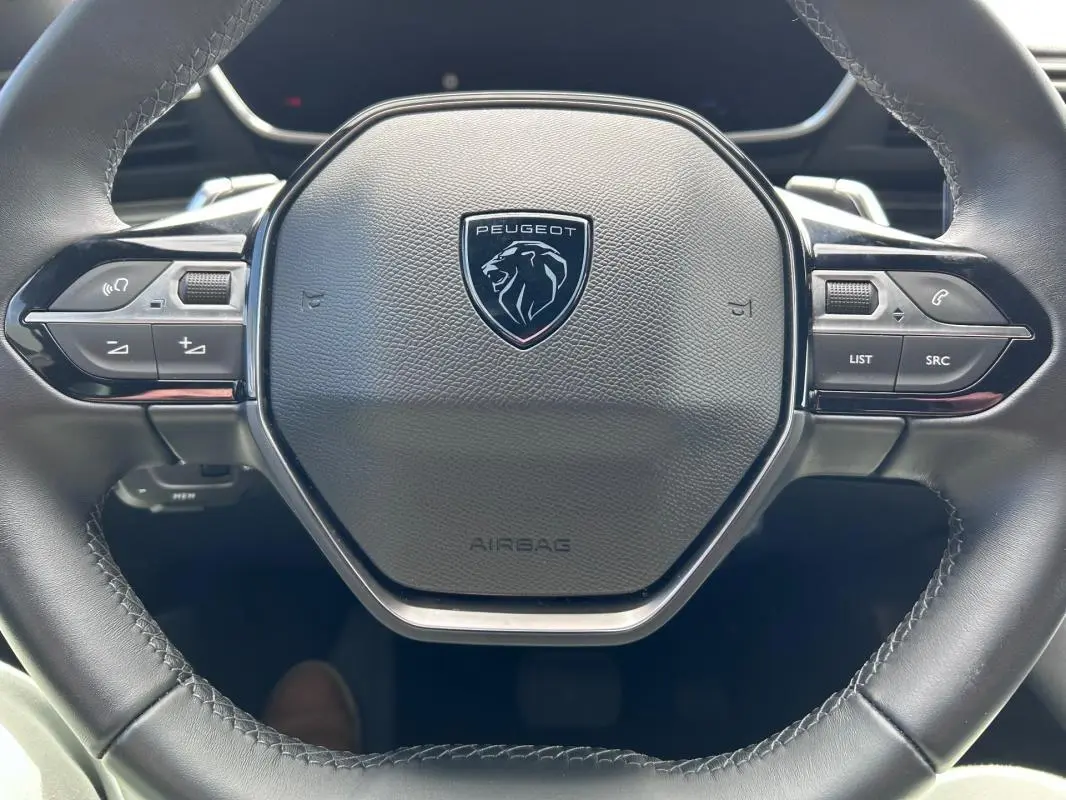 Vue rapprochée du volant cuir noir de la Peugeot 508 Hybrid 225 e-EAT8 avec commandes intégrées.