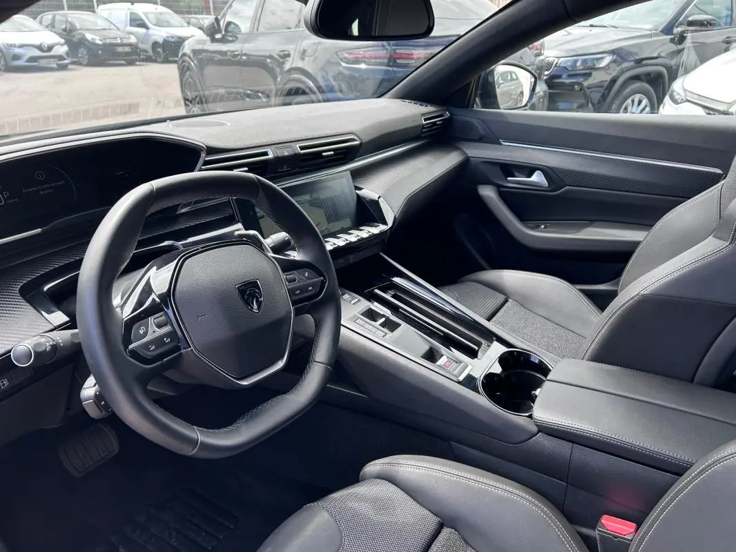 Vue intérieure côté conducteur de la Peugeot 508 Hybrid 225 e-EAT8 Allure 2024 avec volant cuir et écran tactile.