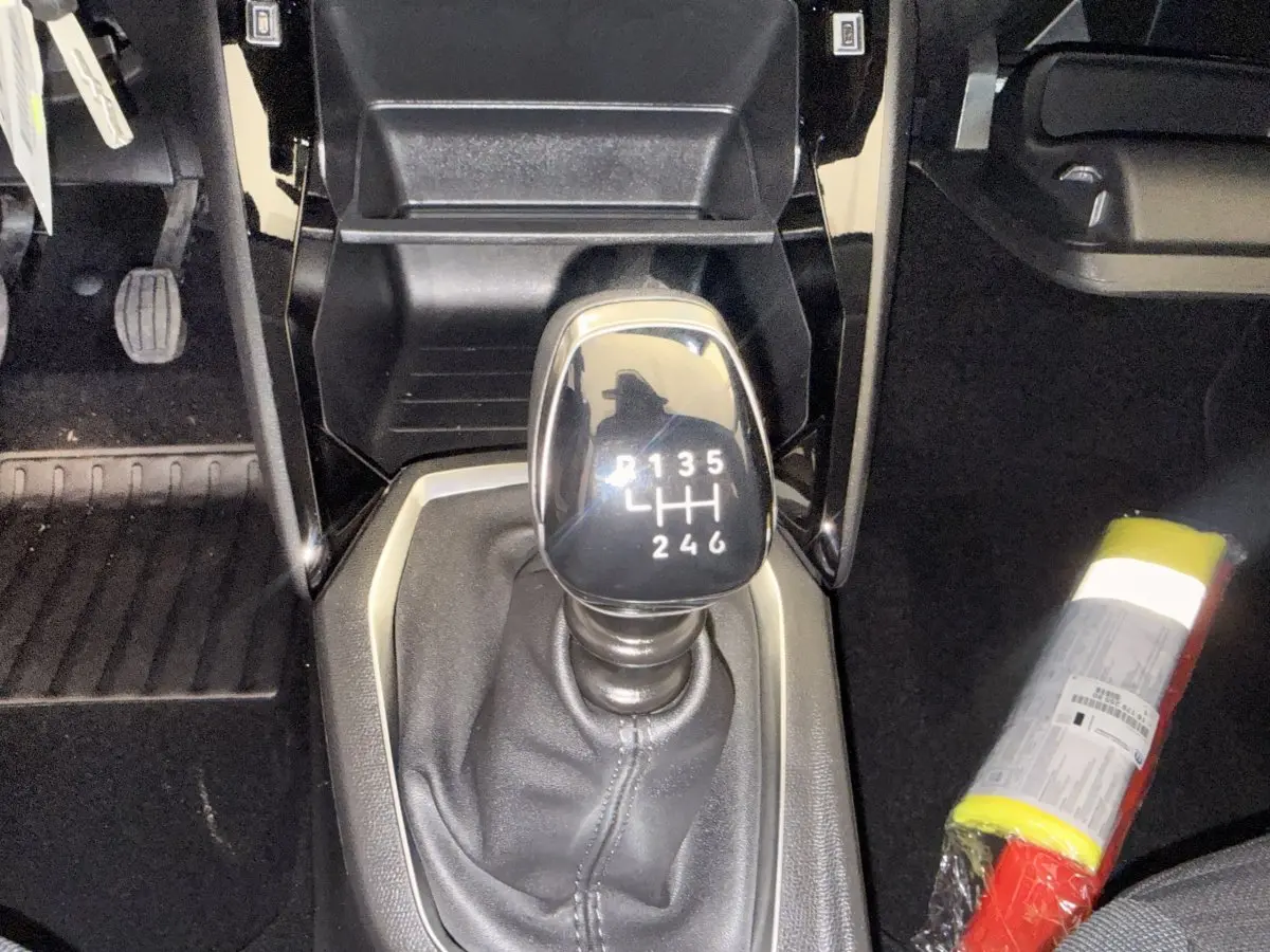 Gros plan sur le levier de vitesse manuel noir de la Peugeot 208, entouré de la console centrale noire et tapis de sol.