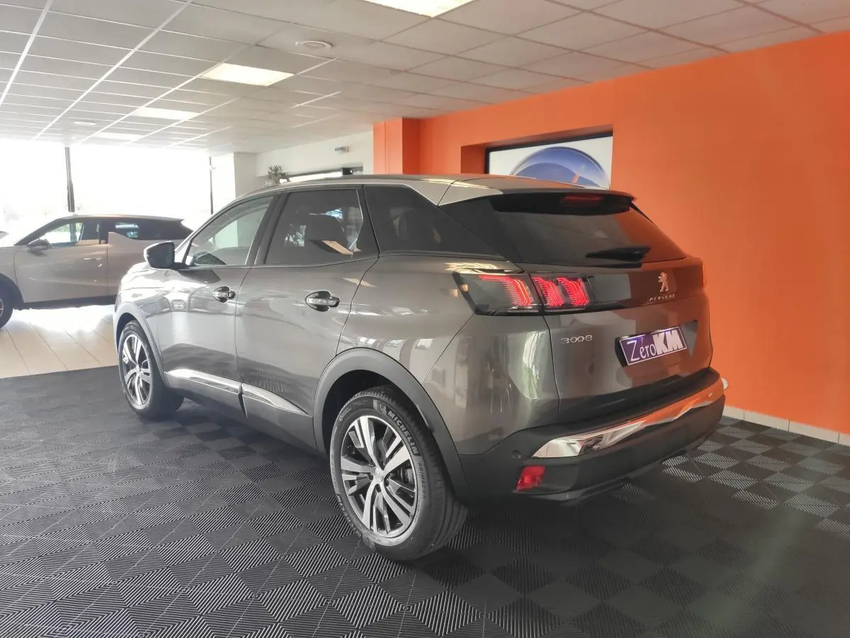 Vue 3/4 arrière droite du Peugeot 3008 gris platinium avec toit noir et jantes bi-ton diamantées dans un showroom.