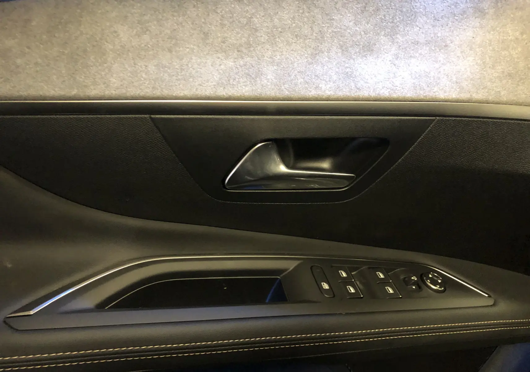 Gros plan sur la poignée intérieure et les commandes de la porte côté conducteur du Peugeot 3008 GT gris platinium toit noir.