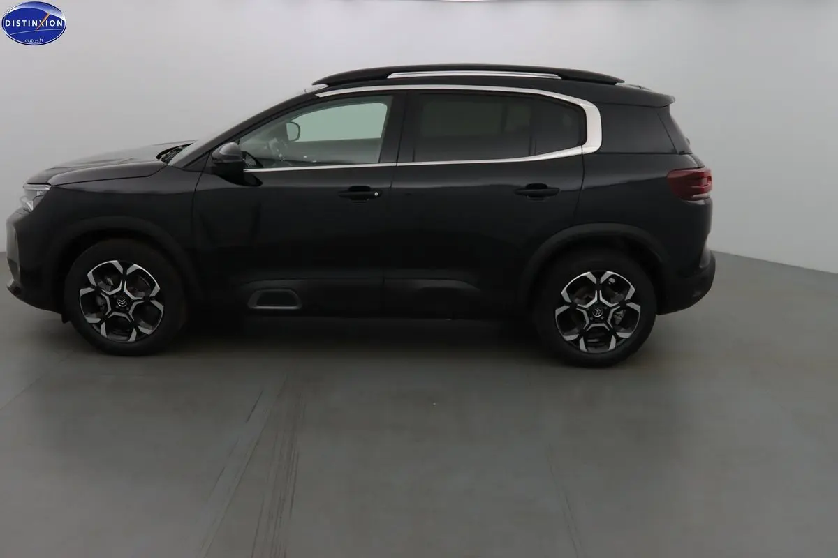 Profil côté gauche du Citroën C5 Aircross noir perle 2022 avec jantes biton et barres de toit visibles.