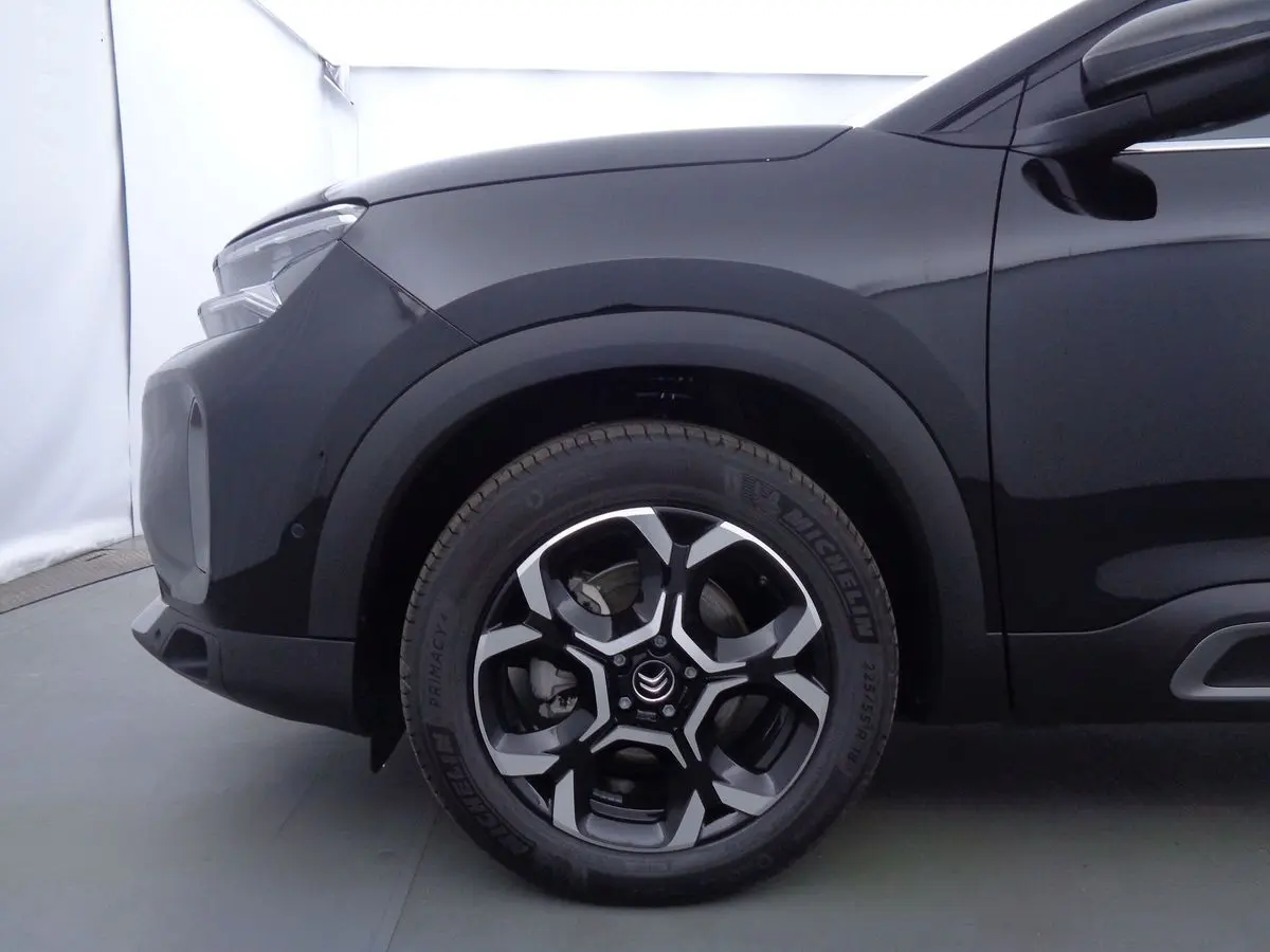 Gros plan sur la roue avant gauche et l'aile d'un Citroën C5 Aircross noir perle, soulignant la jante biton distinctive.