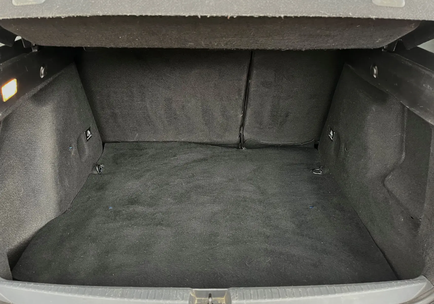 Coffre vide du Dacia Duster 1.5 DCI 2018, vue intérieure arrière, revêtement noir et éclairage latéral allumé.