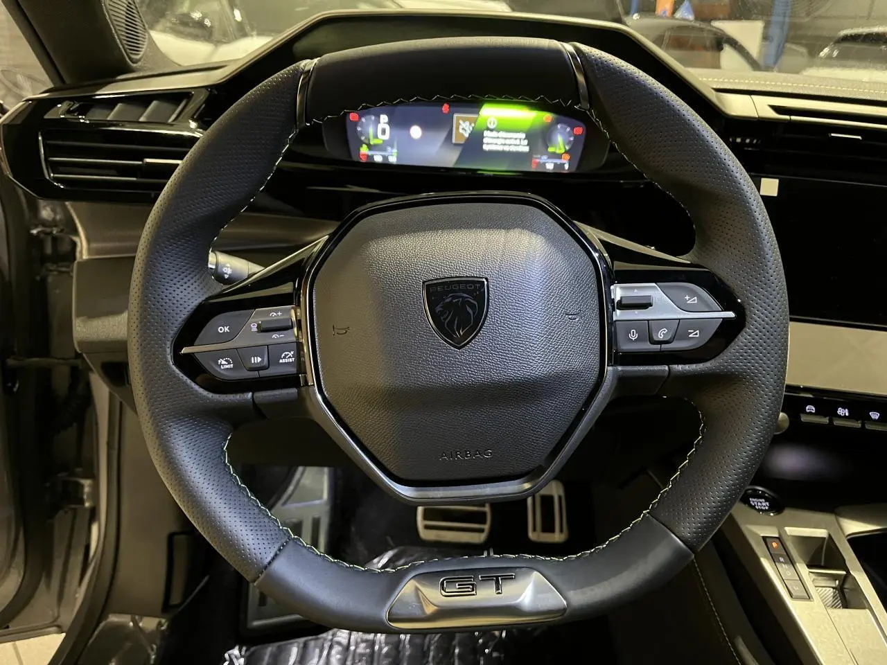 Volant cuir Peugeot 308 GT vu de face avec combiné numérique et pédaliers sport en aluminium visibles