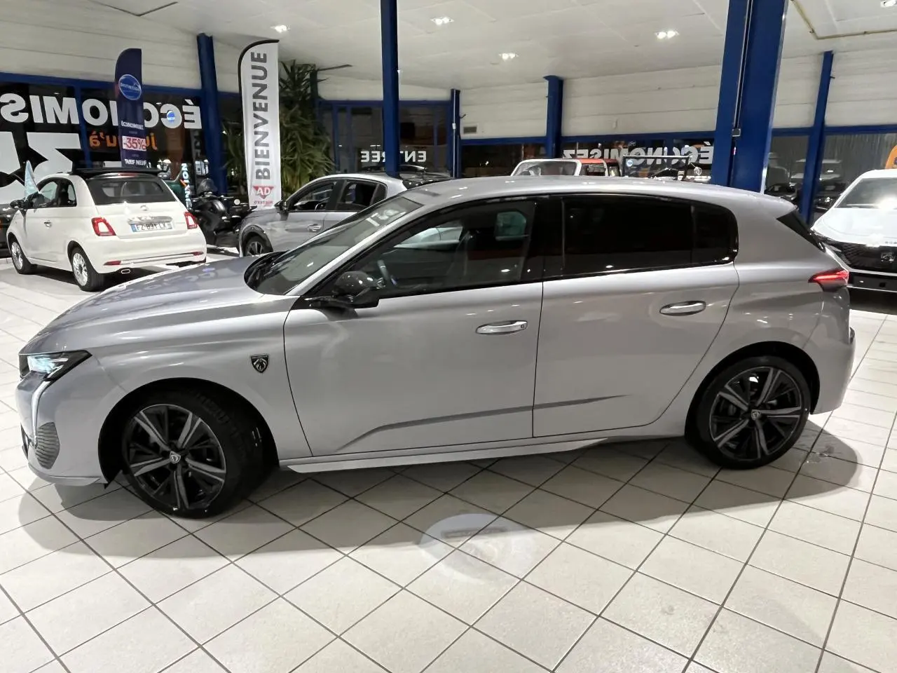 Profil côté gauche d'une Peugeot 308 GT gris Artense avec jantes alliage 18'' Kamakura en showroom.
